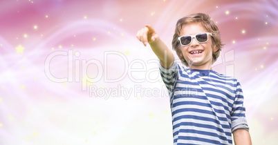 Happy boy wearing sunglasses while pointing over bokeh