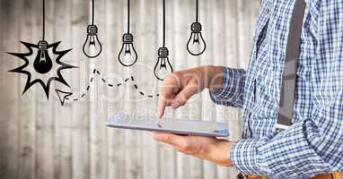 Business man mid section touching tablet against lightbulb graphics and blurry wood panel