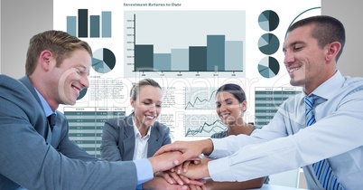 Happy business people stacking hands against graphs