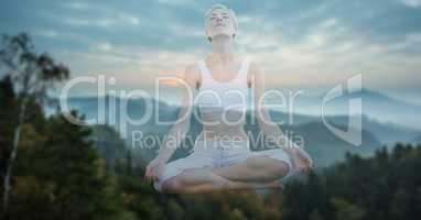 Double exposure meditating woman and mountains