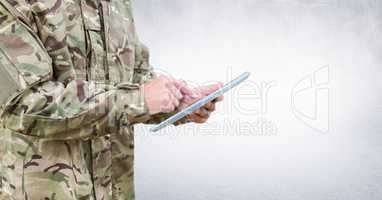 Soldier mid section with tablet against white wall