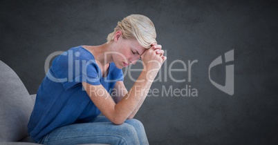 Woman sitting on couch with head on hands against grey background with grunge overlay