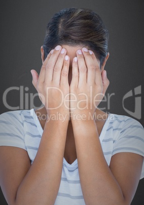 Man with hands over face against grey wall