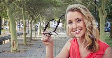 Smiling woman holding eyeglasses in park