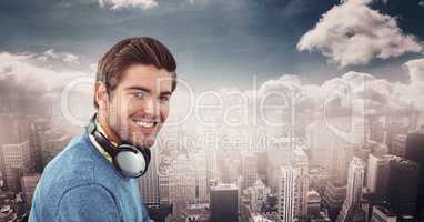 Smiling hipster wearing headphones against city
