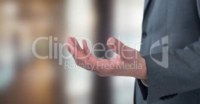 Midsection of businessman offering hand over blurred background