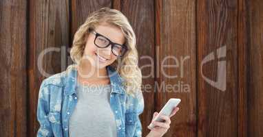 Female hipster holding mobile phone over wooden wall