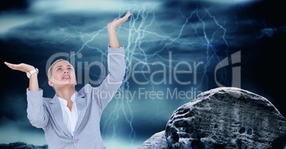 Businesswoman with arms raised by rock against thunderstorm