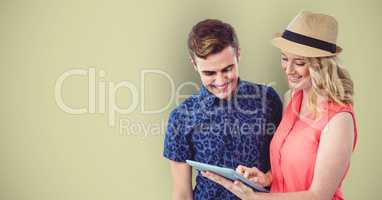 Smiling hipsters using digital tablet against green background