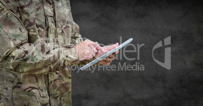 Soldier mid section with tablet and grunge overlay against grey wall