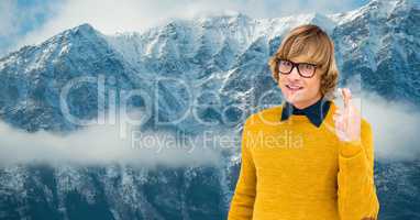 Male hipster with crossed fingers against snow covered mountains