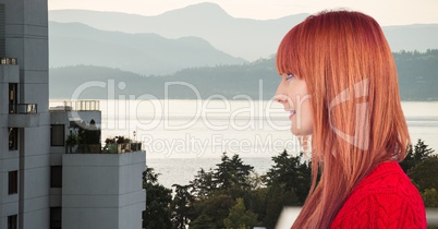 Side view of redhead woman with building and lake in background