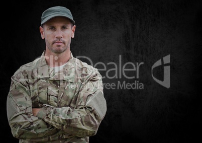 Soldier with arms folded against black grunge background