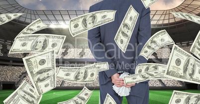 Midsection of businessman holding money behind back at football stadium representing corruption