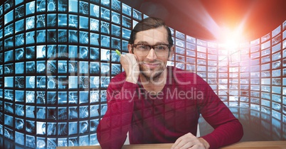 Smiling hacker sitting against screens