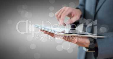 Business man mid section with tablet behind bokeh against grey background