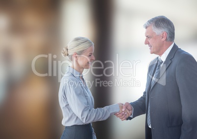 Smiling business people shaking hands against blurred background