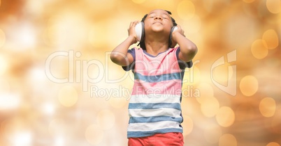 Boy listening music through headphones over bokeh