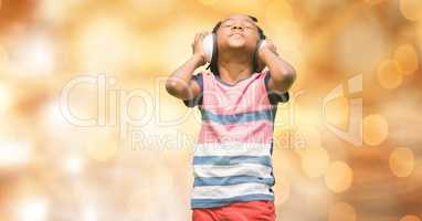 Boy listening music through headphones over bokeh