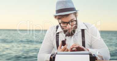 Hipster smoking pipe while using typewriter against sea