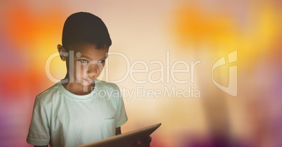 Boy looking away while holding digital tablet over bokeh