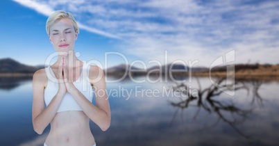 Double exposure of woman with hands clasped performing yoga against lake