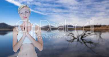 Double exposure of woman with hands clasped performing yoga against lake