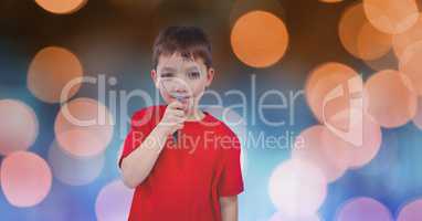 Little boy holding magnifying glass over blur background