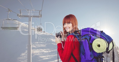 Portrait of happy female hiker holding camera on snow covered mountain