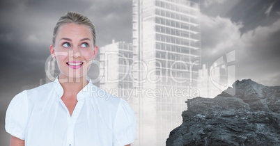 Thoughtful businesswoman smiling against rock and buildings