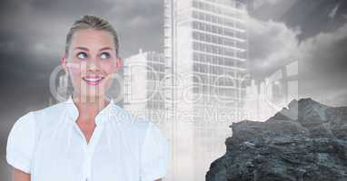 Thoughtful businesswoman smiling against rock and buildings