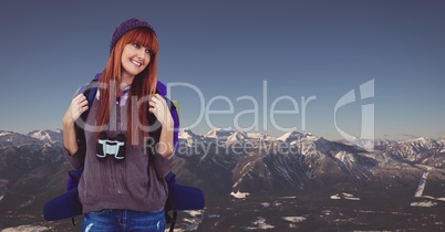 Happy female traveler carrying backpack on mountain against clear sky