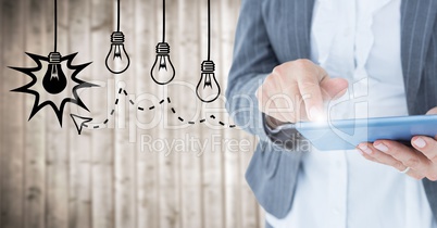 Business woman mid section touching tablet with flare against lightbulb graphics and blurry wood pan