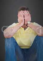 Man sitting and crying against grey wall