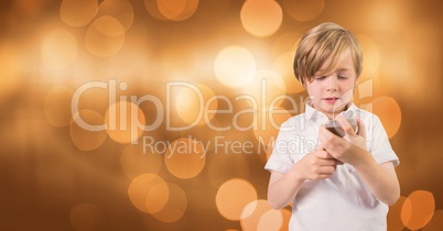 Little boy holding mobile phone over bokeh