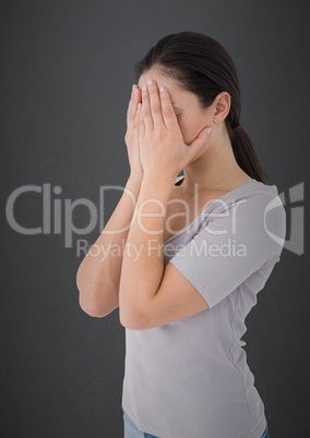 Woman with hands on face against grey wall