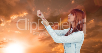 Redhead woman with arms raised against sky during sunset
