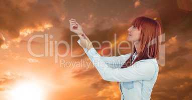 Redhead woman with arms raised against sky during sunset