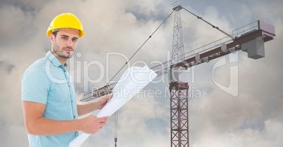 Architect holding blueprint by cranes against sky