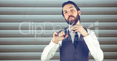 Confident hipster cutting beard against wall
