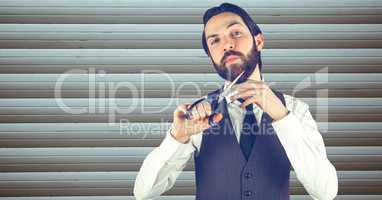 Confident hipster cutting beard against wall