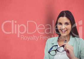 Portrait of happy female hipster holding eyeglasses against red background