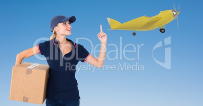 Delivery woman with parcel pointing at airplane