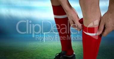 Close-up of soccer player adjusting sock on field