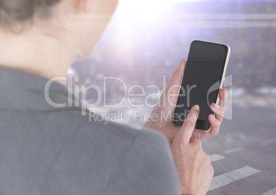 Business woman over shoulder with phone against blurry street with flares