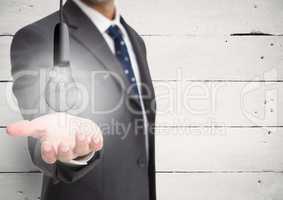 Business man hand out with glowing lightbulb against white wood panel