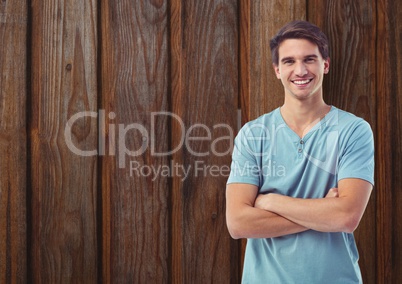 Happy young man standing arms crossed against wooden wall