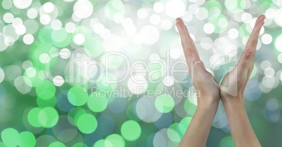 Close-up of hands against green glowing bokeh