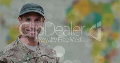 Soldier smiling against blurry map with bokeh