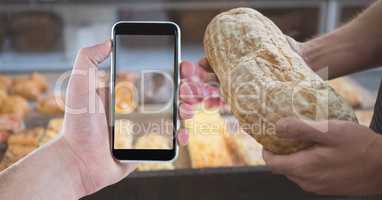 Cropped image of people holding smart phone and bread in coffee shop